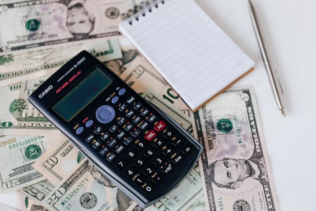 Dollars with calculator and notebook and pen on a table