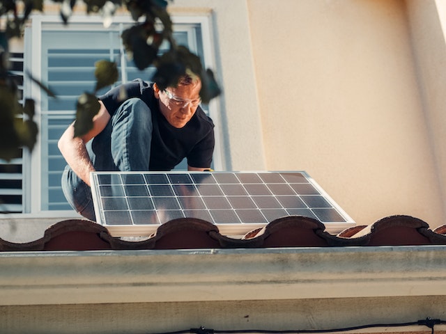 person inspecting solar panel on roof