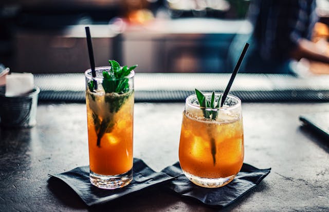 two orange cocktails with herbs